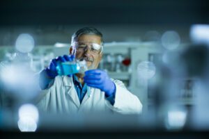 male scientist pouring liquid into beaker